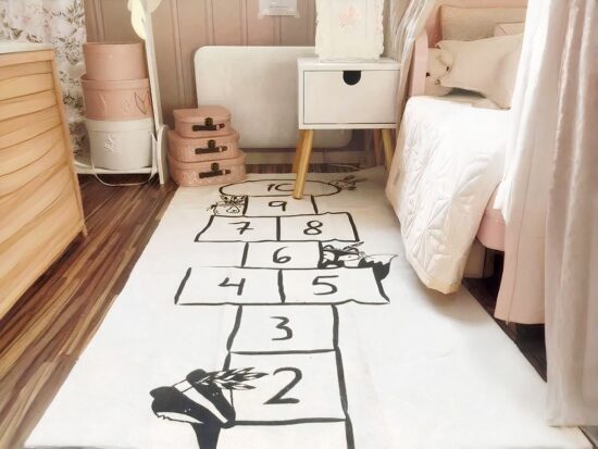 tapis blanc illustré avec une marelle noire jouets pour enfants et lit avec une couverture blanche