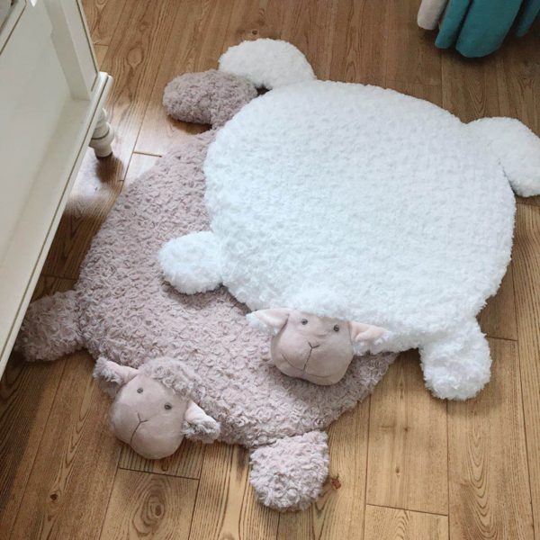 Un tapis de sol pour enfant rond qui ressemble a un mouton un rose et un blanc