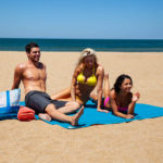 Tapis de plage bleu sur le sable , un homme, une femme et un enfant en maillot sur la serviette