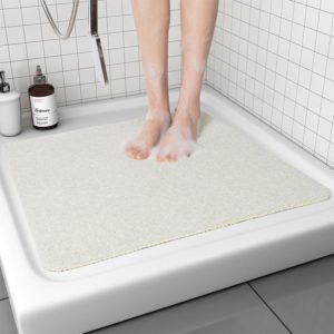 tapis de douche blanc , bac à douche blanc et pieds de femme mouillés