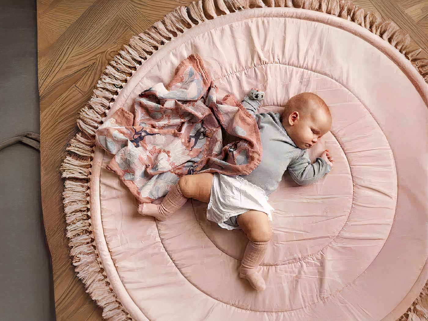 1445-Kfxbsc.jpg tapis de sol rond et rose avec des franges et un bébé en barboteuse et un doudou rose
