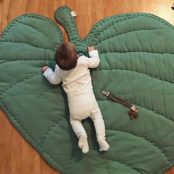 tapis de sol vert en forme de feuille d'arbre et bébé en barboteuse blanche