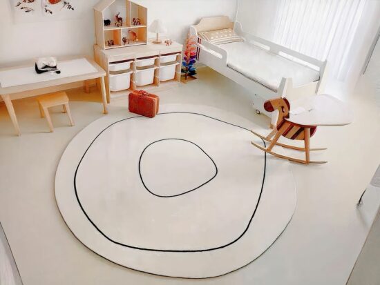 tapis rond blanc avec liseré noir , cheval à bascule et lit d'enfant blanc