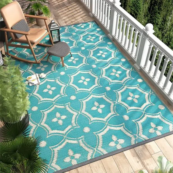 tapis de terrasse bleu avec motifs ronds , terrasse avec rembarde blanche et fauteuil à bascule