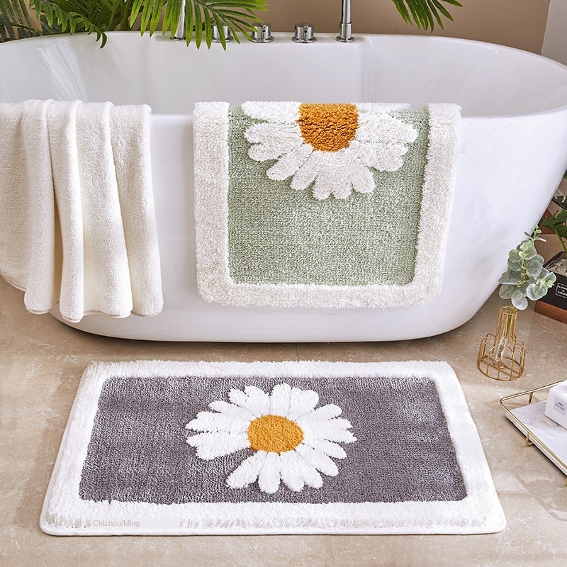 tapis de salle de bain illustré d'une marguerite posés sur une baignoire blanche