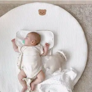 Tapis rond blanc avec une petite tête d'ours brodée et un bébé endormi