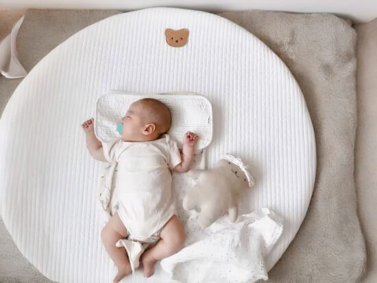 Tapis rond blanc avec une petite tête d'ours brodée et un bébé endormi