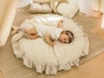 Grand tapis rose épais avec une petite fille en robe blanche allongé dessus