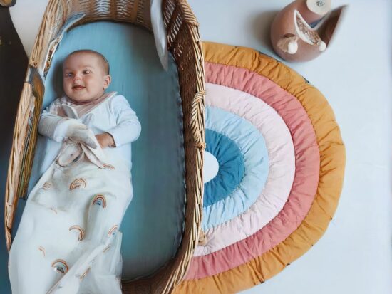 Petit tapis en demi cercle motif arc en ciel et un bébé dans son couffin