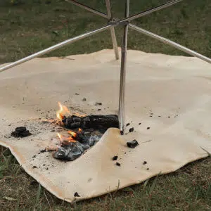 Tapis de barbecue avec de la braise incandescente et un pied de barbecue