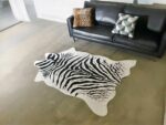 Tapis zèbre imitation de peau devant canapé noir en cuir
