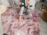 Tapis cocooning rectangulaire rose foncé installé dans une chambre et sur lequel est assise une jeune fille en train de lire un livre