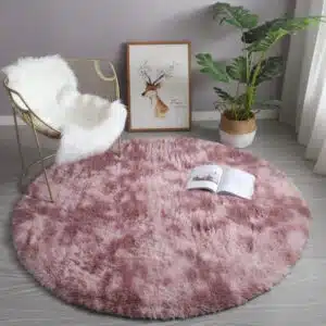 Tapis cocooning rond rose installé dans un salon aux pieds d'une chaise à bascule