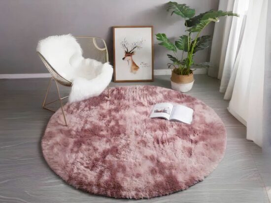 Tapis cocooning rond rose installé dans un salon aux pieds d'une chaise à bascule