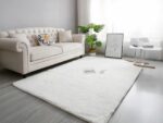 Tapis cocooning nordique rectangulaire blanc extra doux installé dans un salon aux pieds d'un canapé