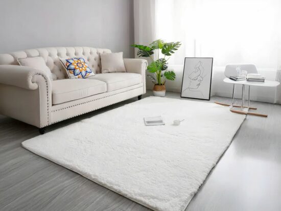 Tapis cocooning nordique rectangulaire blanc extra doux installé dans un salon aux pieds d'un canapé